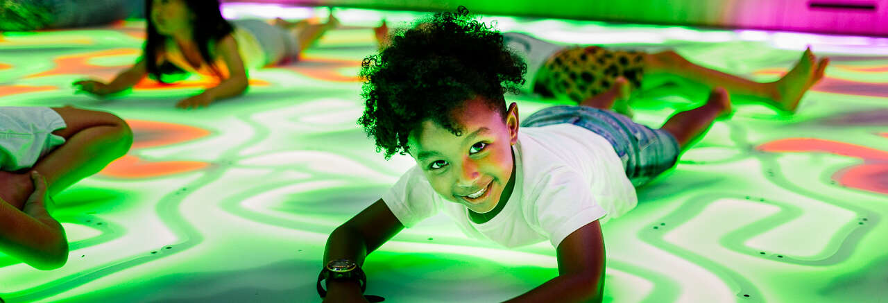 Four young guests enjoying themselves by "getting down" on the Frog Disco dancefloor, with one smiling to the camera.
