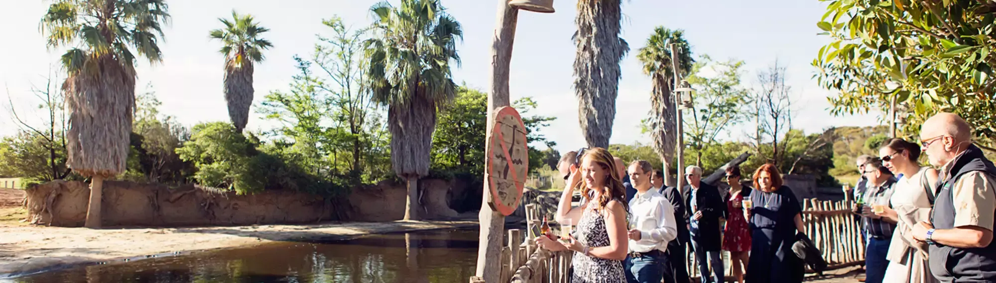 A group of people standing on a Boardwalk overlooking a river.