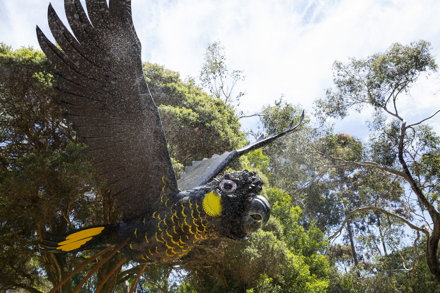 The Parrot Sculpture, seen from the front-right behind a spray of mist.
