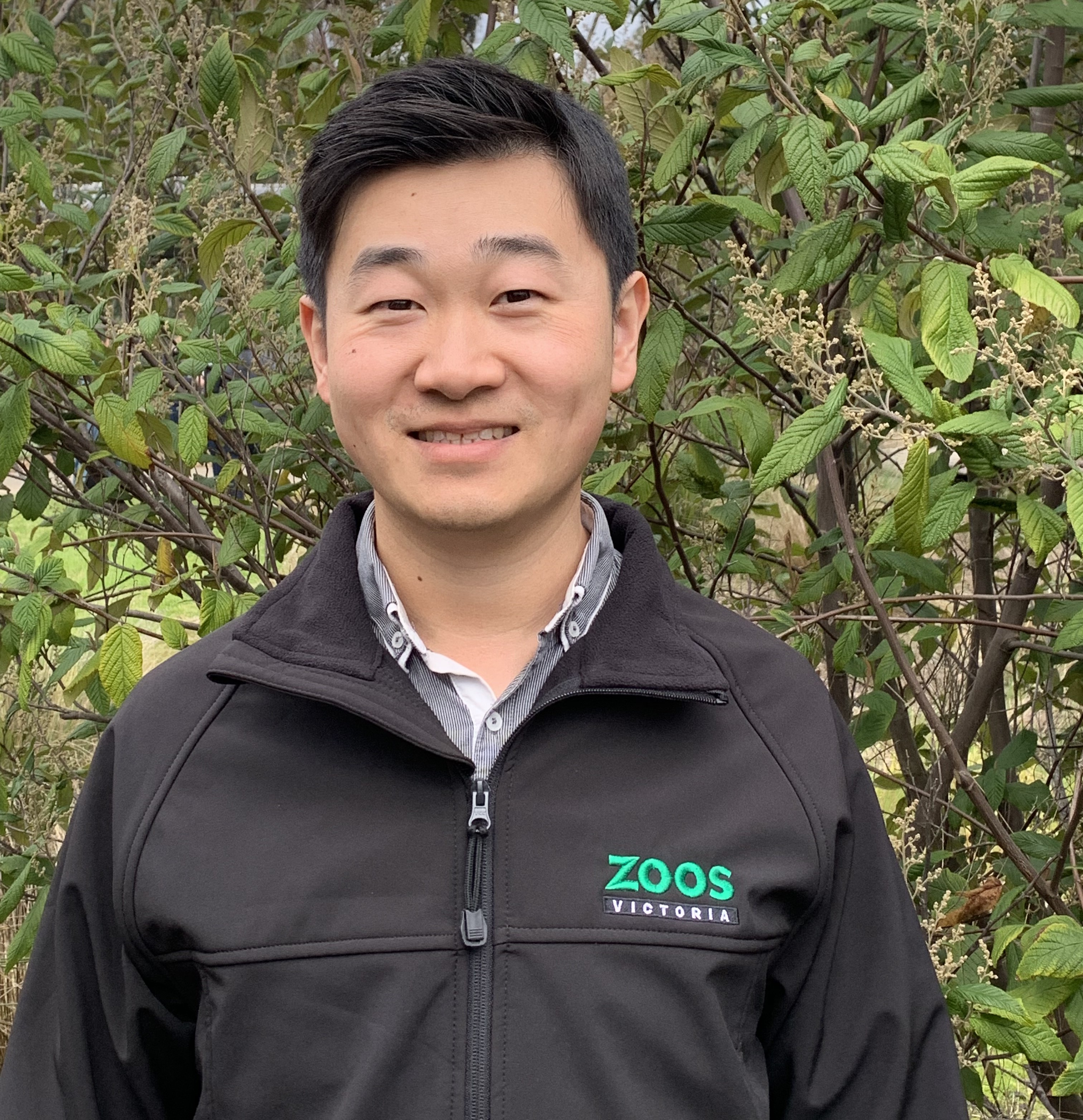 Portrait of Vet Tian, in front of a leafy backdrop.