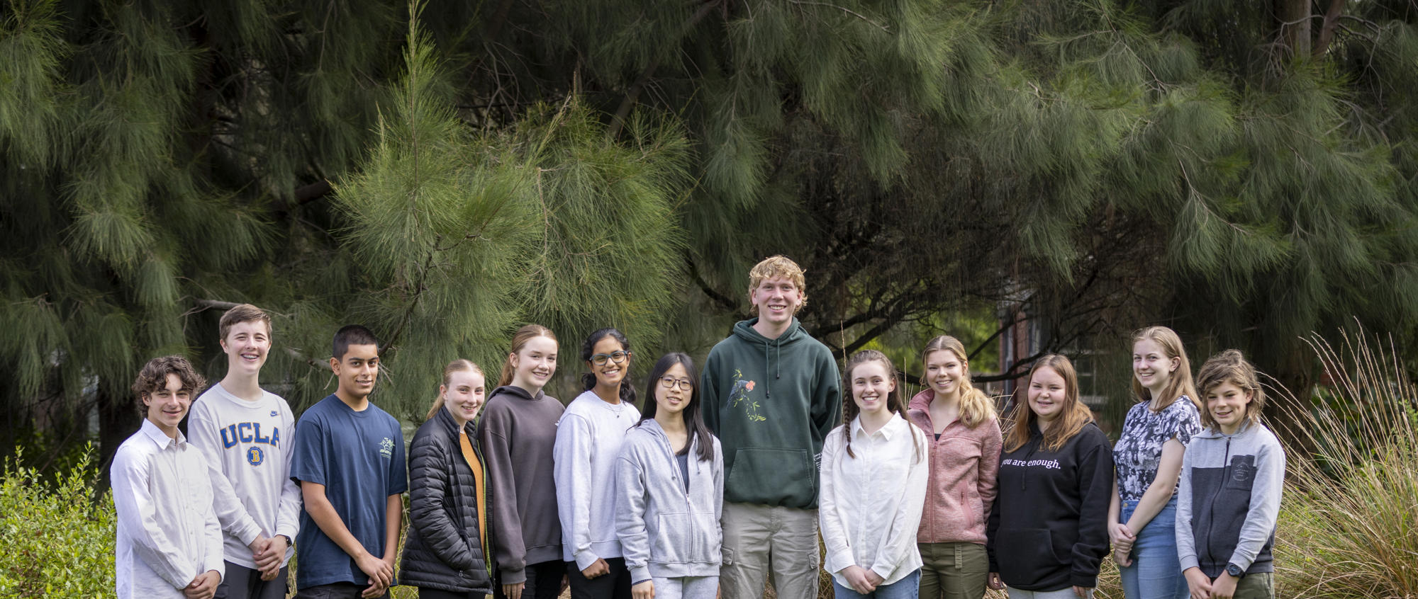 The thirteen then-active members of ZV's Youth Advisory Committee, rowed up trees and smiling to the camera.