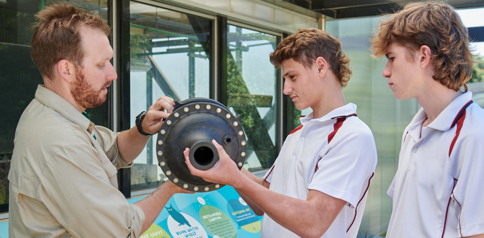 Two high school students with Melbourne Zoo educator investigating an object. 