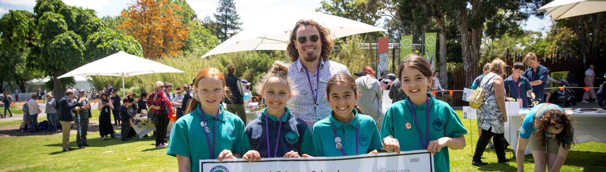 Four students and their teacher posing, as they hold a cheque at the Fighting Extinction Schools Showcase.