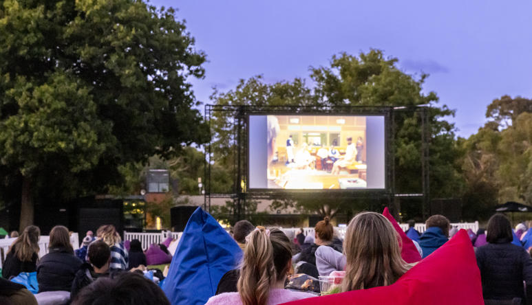An outdoor movie screening on Melbourne Zoo's North Lawn at dusk.