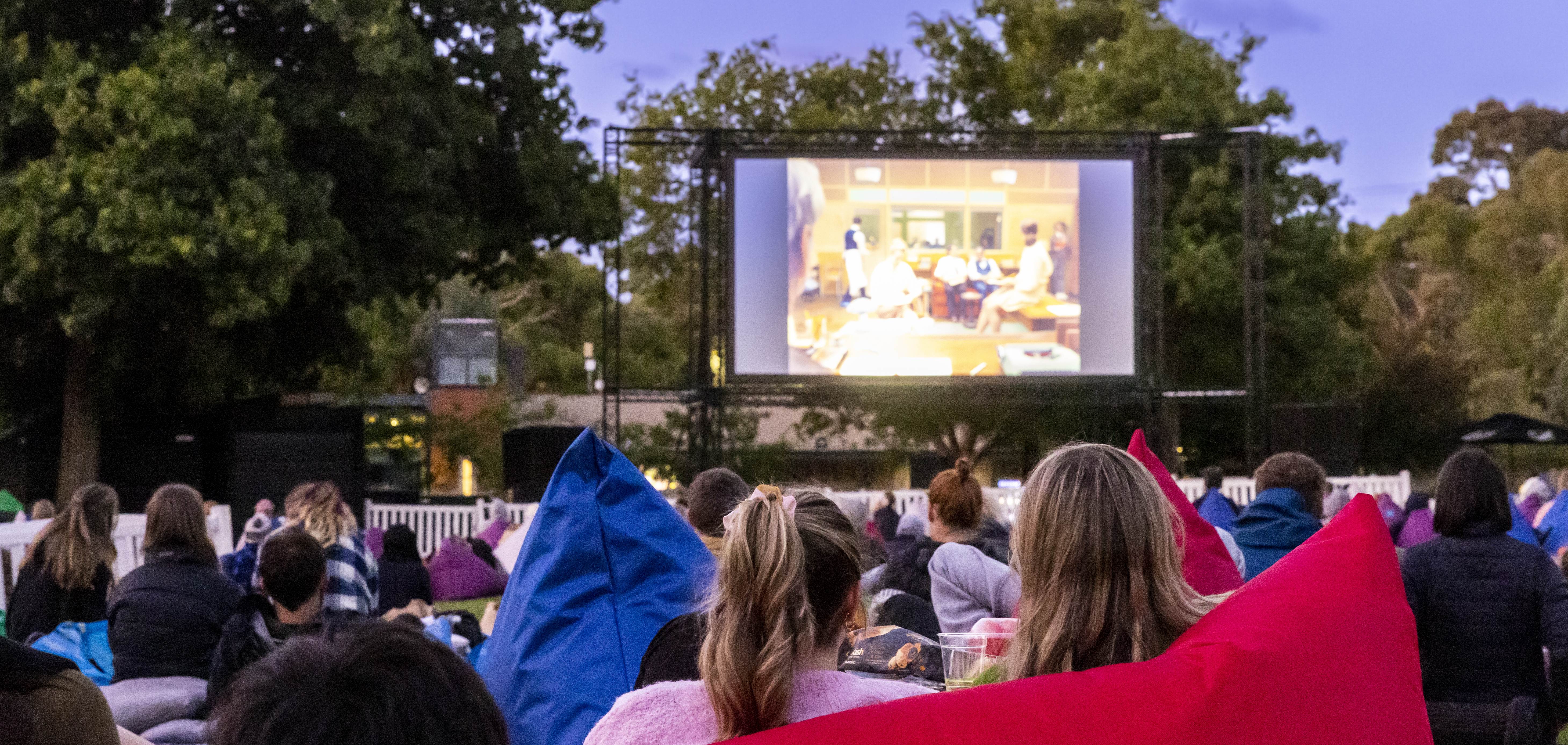 An outdoor movie screening on Melbourne Zoo's North Lawn at dusk.
