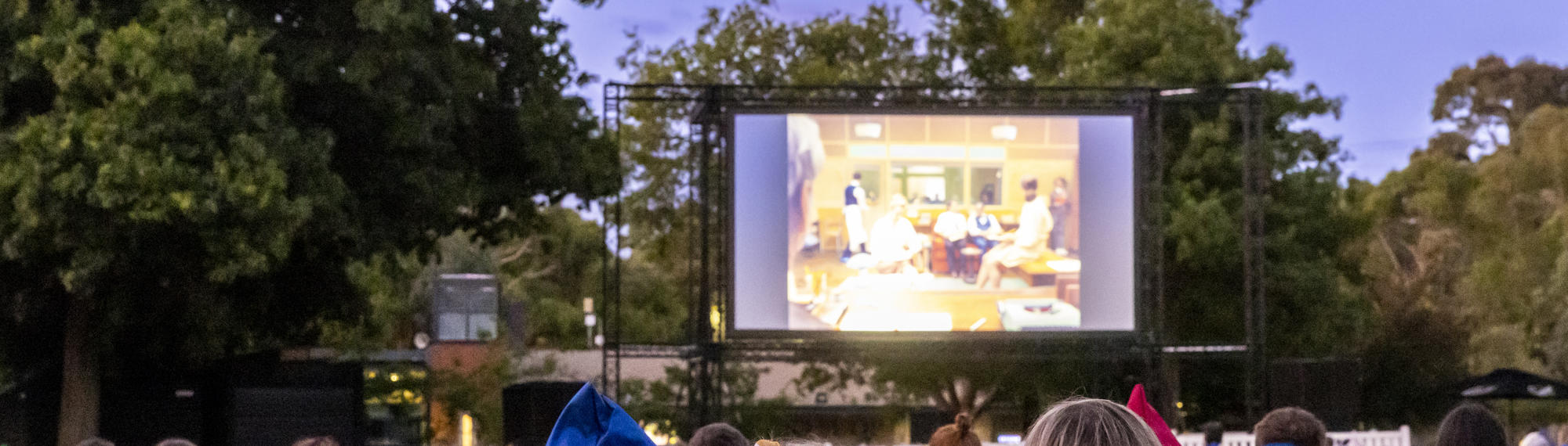 An outdoor movie screening on Melbourne Zoo's North Lawn at dusk.