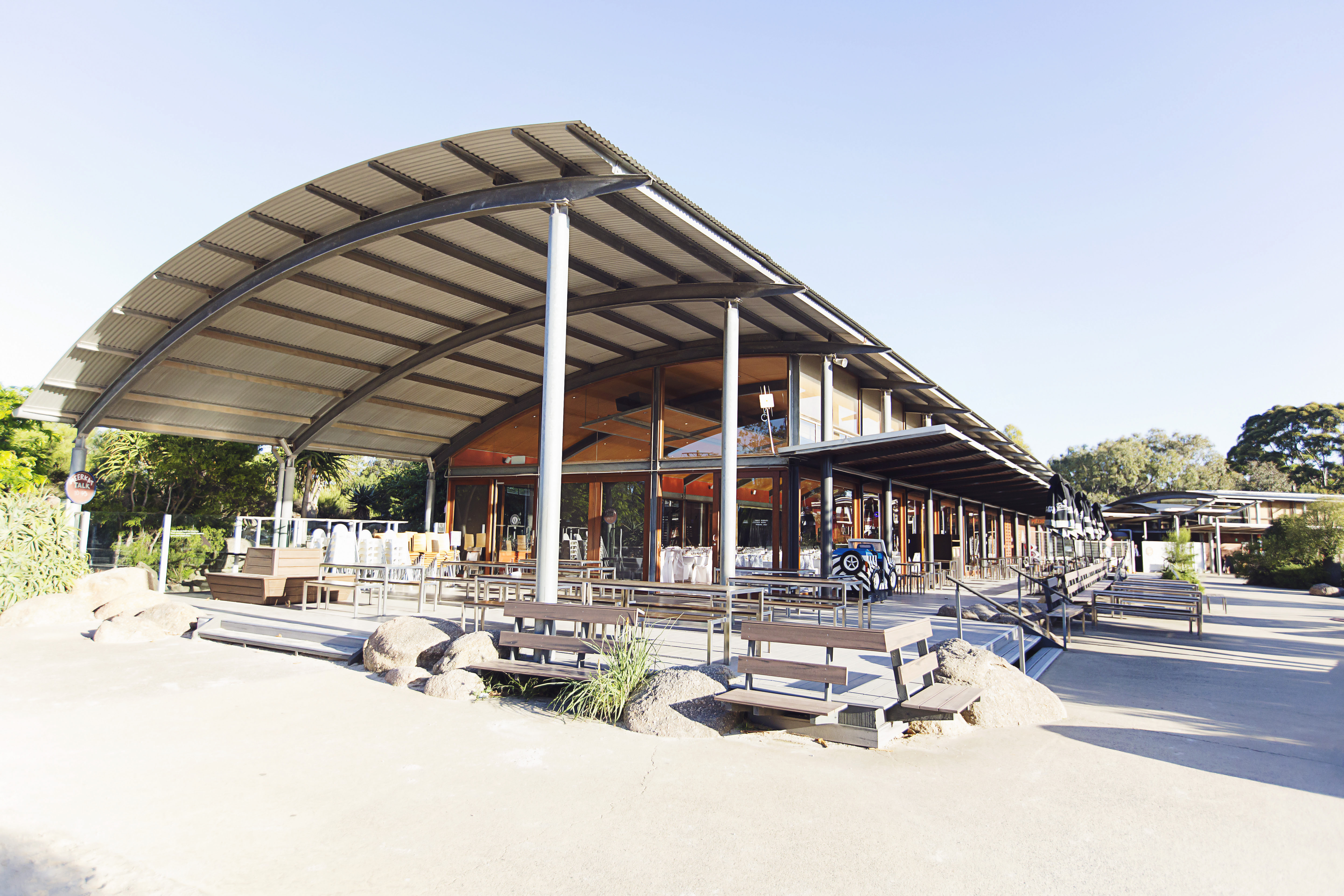 A building with a curved roof and picnic benches out the front.