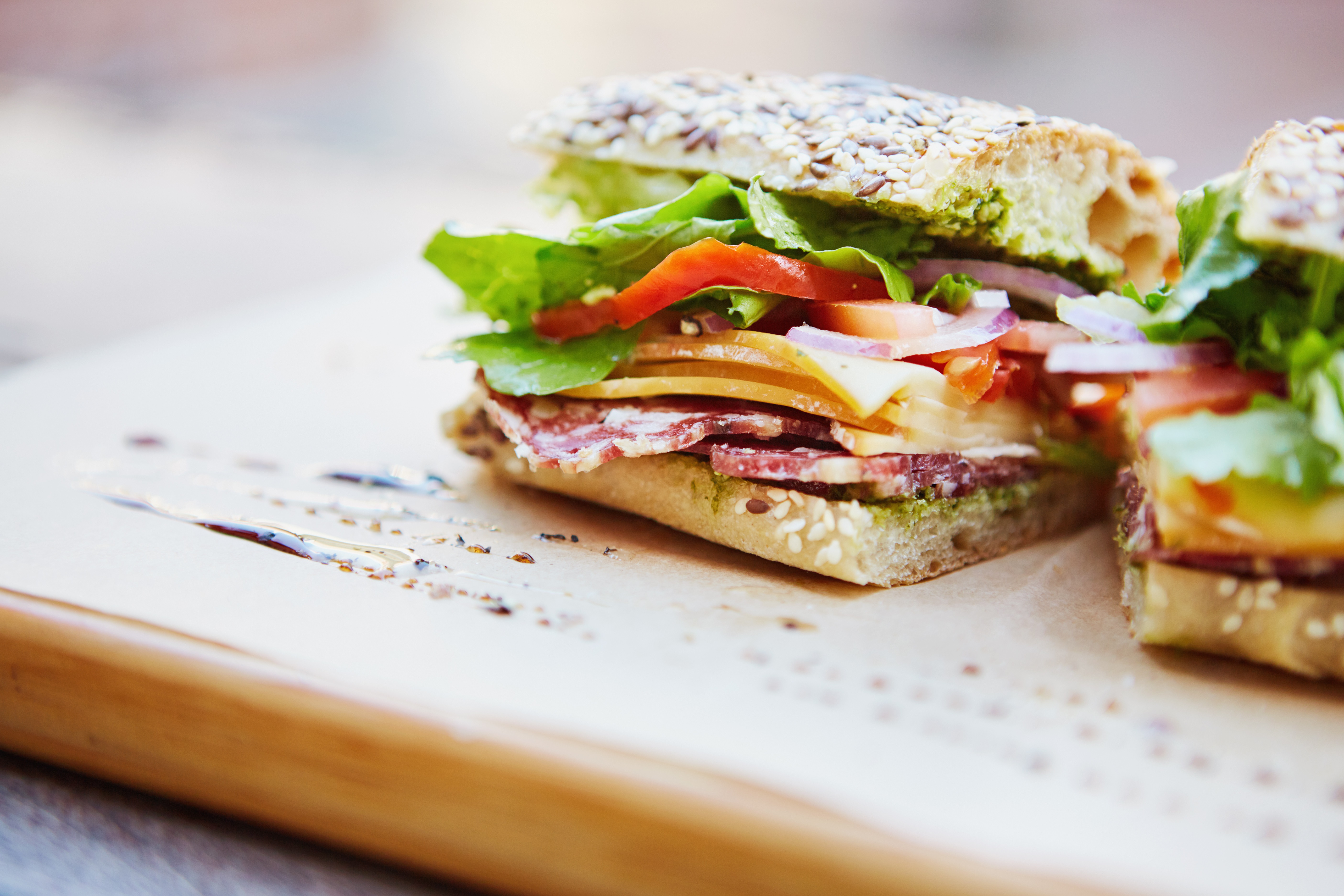 Close-up of a sandwich made of salami, cheese, tomato, red onion and lettuce, on wholegrain bread.