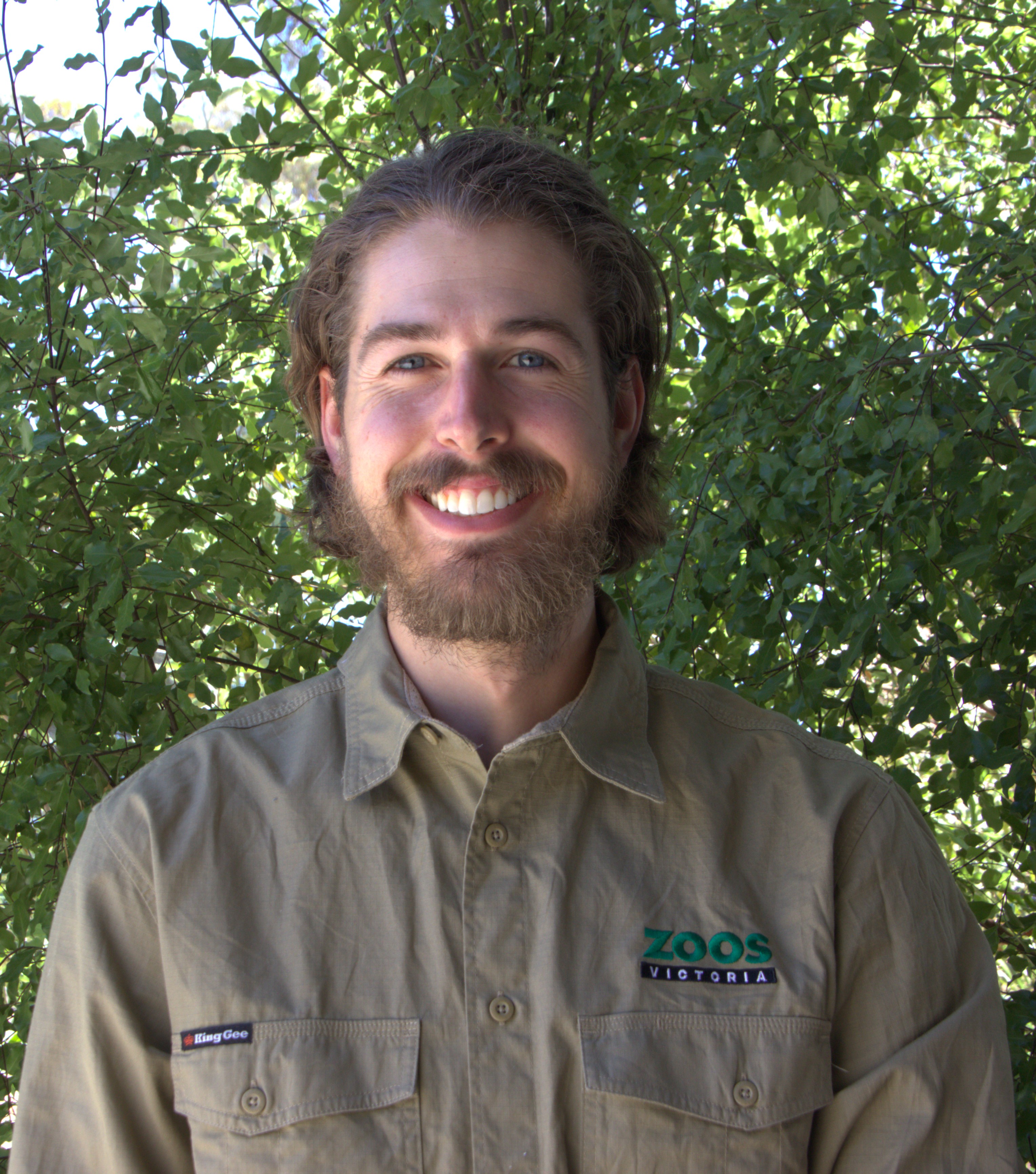 Portrait of Keeper Aaron, in front of a leafy backdrop.