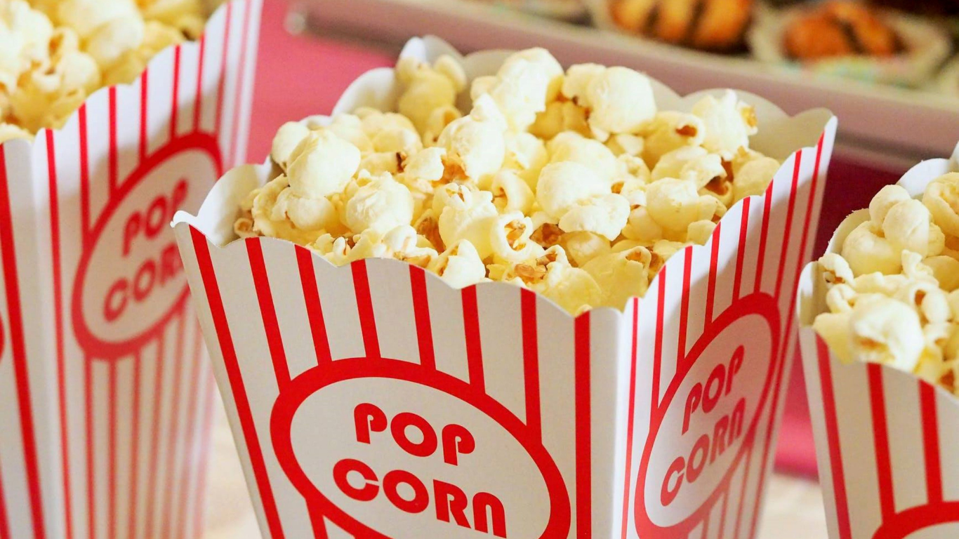 Close-up of three popcorn tubs in a row, decorated in red stripes on white.