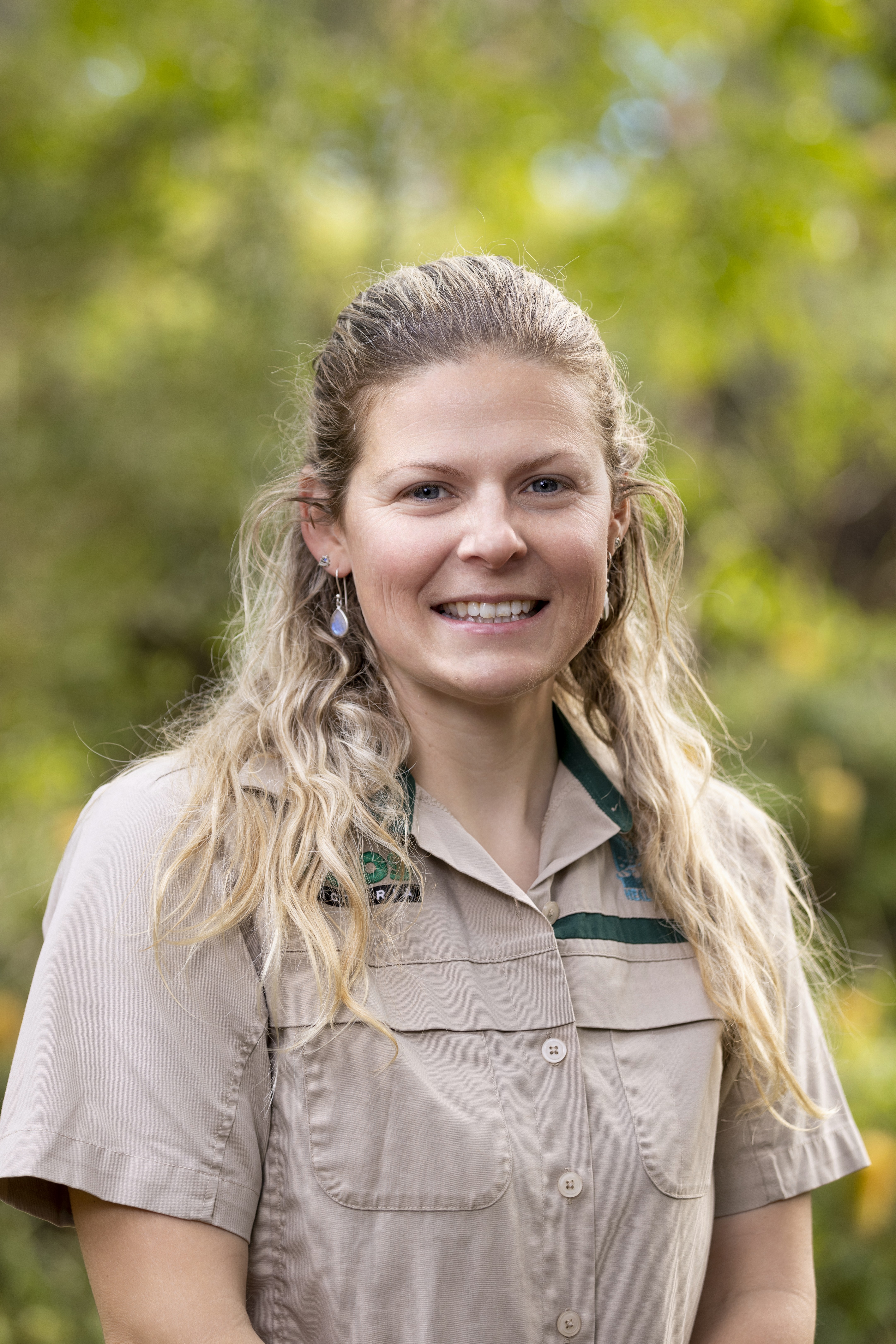 Veterinary Doctor Jessica Thomas, smiling to the camera against a green, leafy backdrop